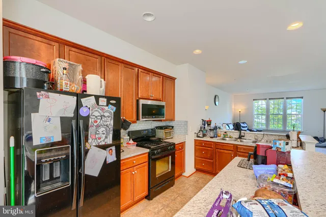 a large kitchen with stainless steel appliances kitchen island granite countertop a refrigerator and a stove top oven