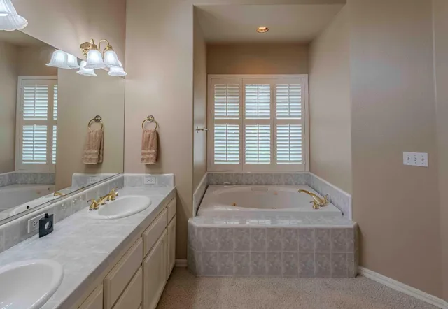 a spacious bathroom with a tub sink and mirror