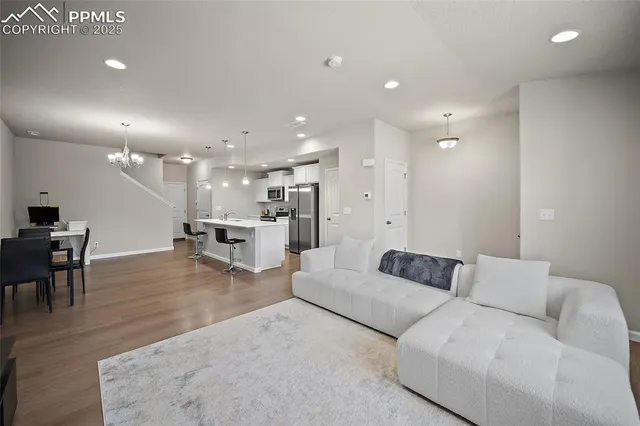 a living room with furniture and a dining table with wooden floor