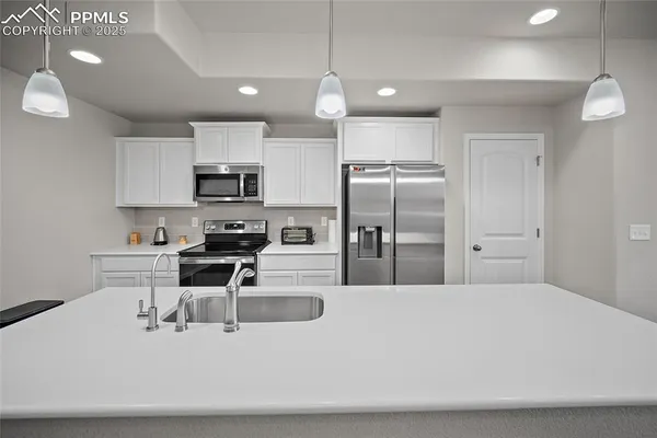 a kitchen with stainless steel appliances a refrigerator a stove a sink a dining table and chairs