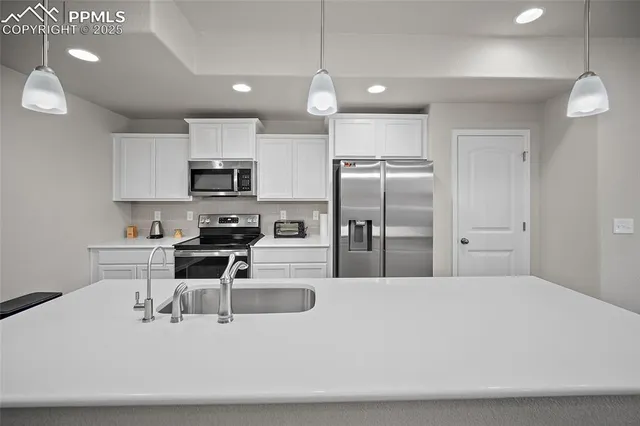 a kitchen with stainless steel appliances a refrigerator a stove a sink a dining table and chairs