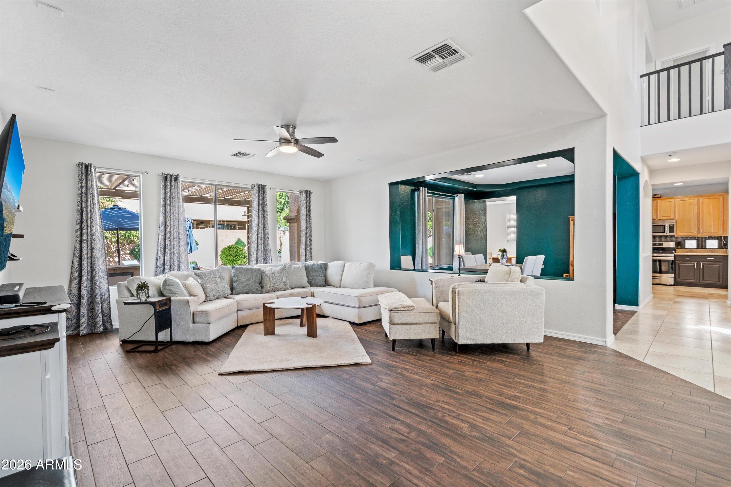 16018 West Shangri La Road Surprise, AZ 85379 - Photo 17 of 40 a living room with couches and kitchen view with wooden floor