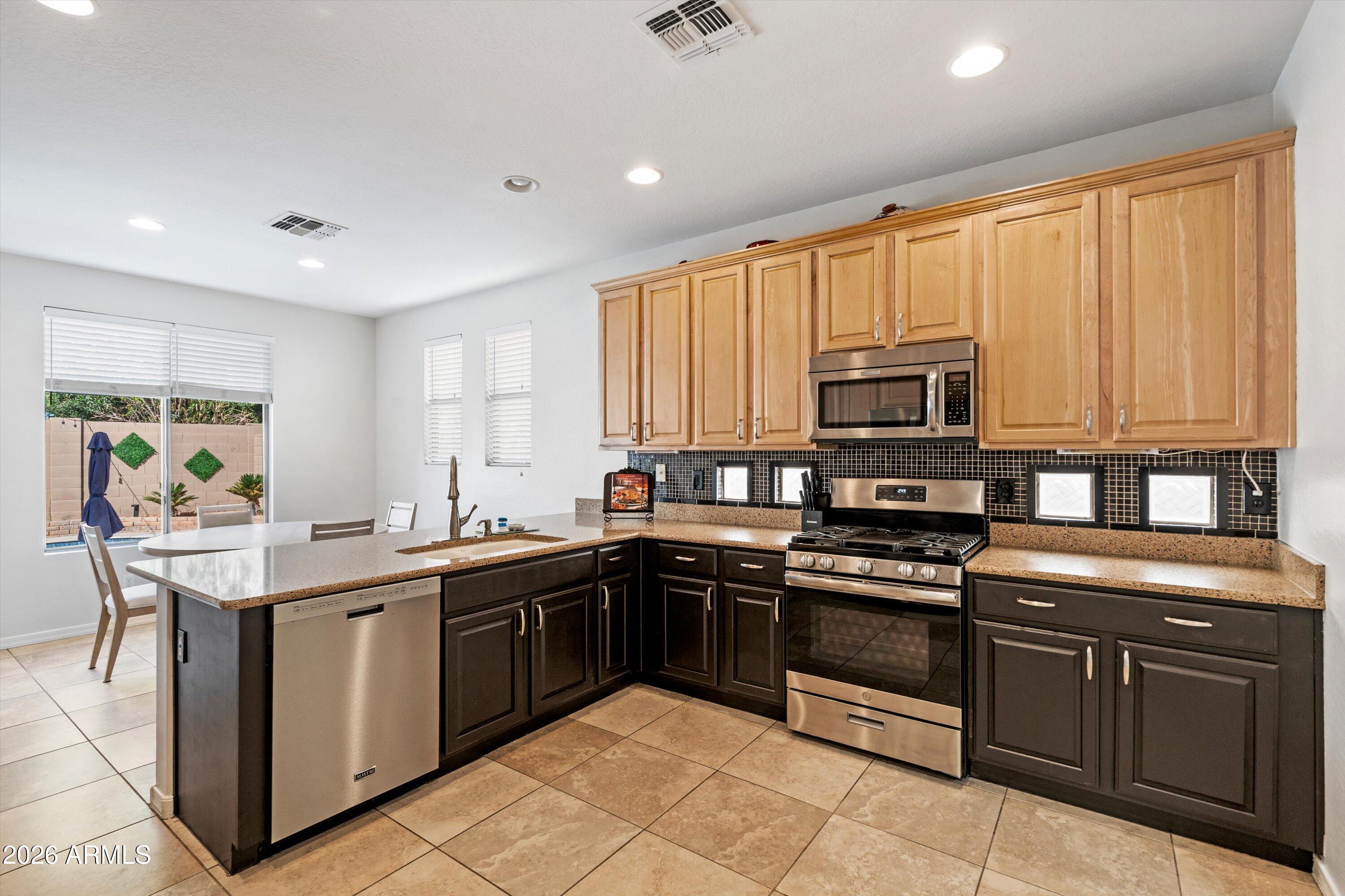 16018 West Shangri La Road Surprise, AZ 85379 - Photo 20 of 40 a kitchen with stainless steel appliances granite countertop a stove a sink dishwasher and a microwave