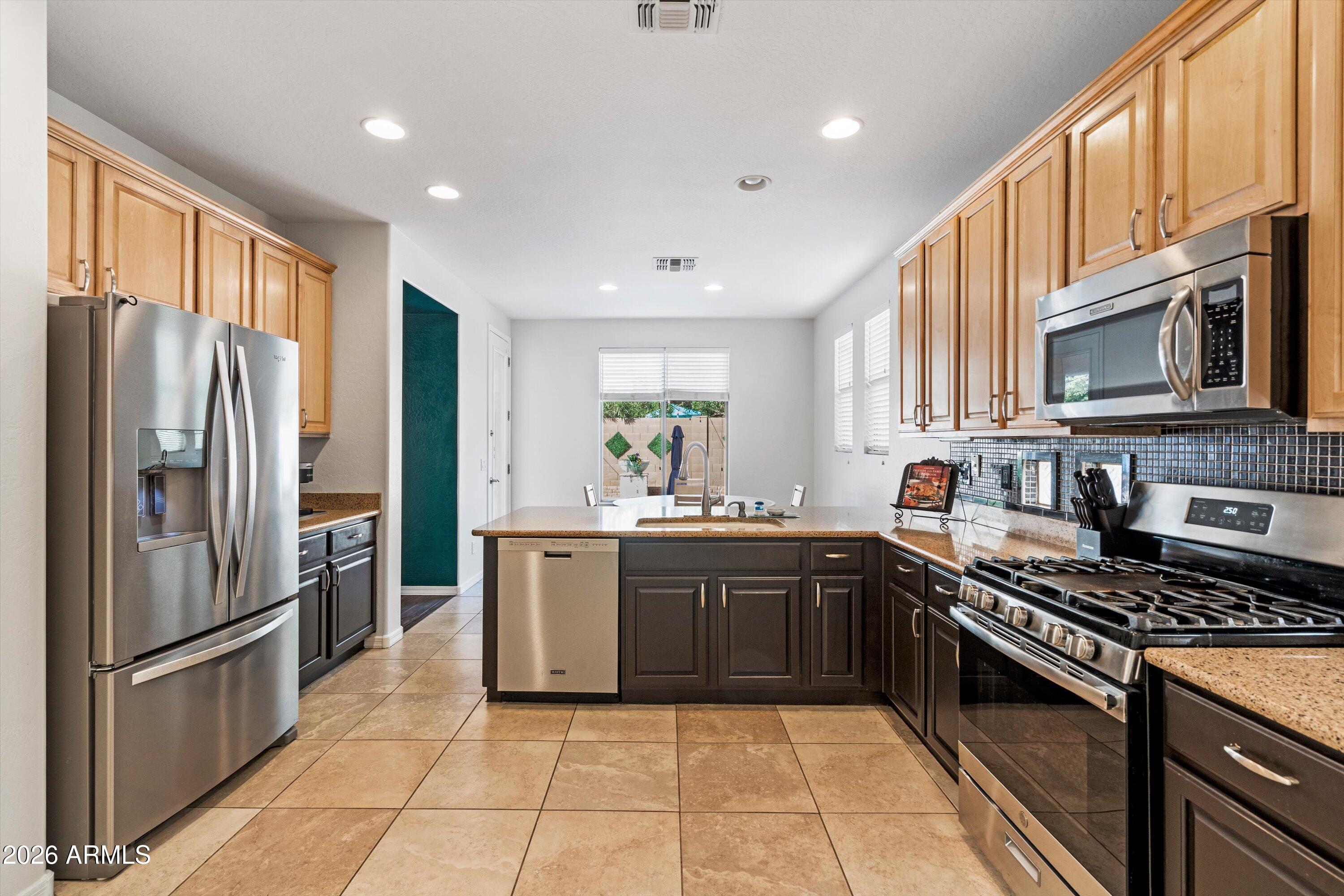 16018 West Shangri La Road Surprise, AZ 85379 - Photo 21 of 40 a large kitchen with stainless steel appliances granite countertop a stove top oven a refrigerator and a granite counter tops
