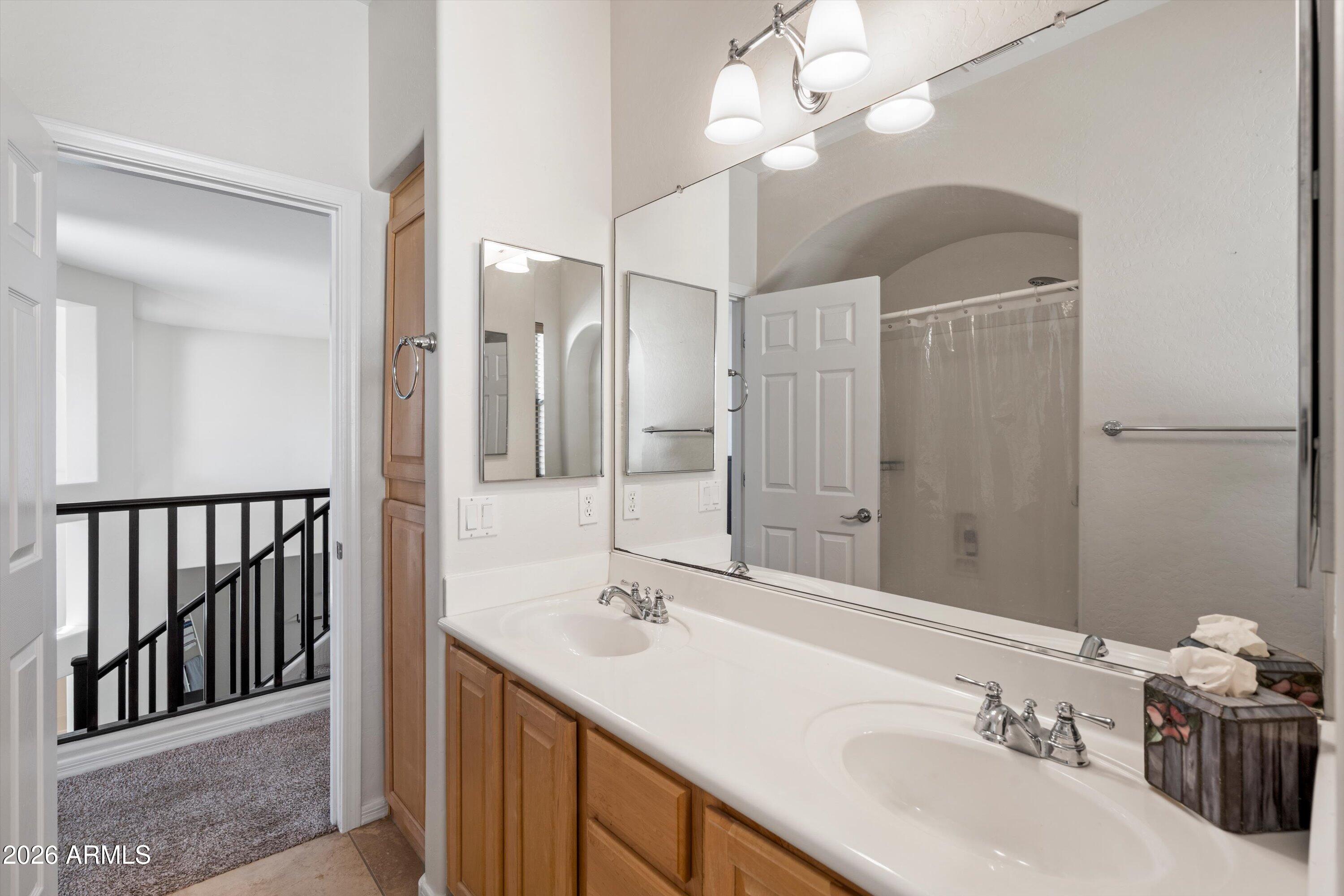 16018 West Shangri La Road Surprise, AZ 85379 - Photo 34 of 40 a bathroom with a double vanity sink a mirror and a shower