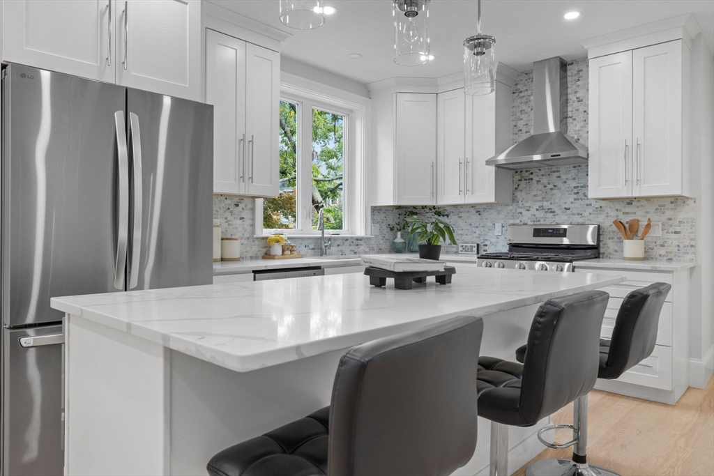 31 Rodman Street, Unit 2 Boston, MA 02130 - Photo 4 of 40 a kitchen with stainless steel appliances granite countertop a stove a refrigerator a sink a dining table and chairs with wooden floor