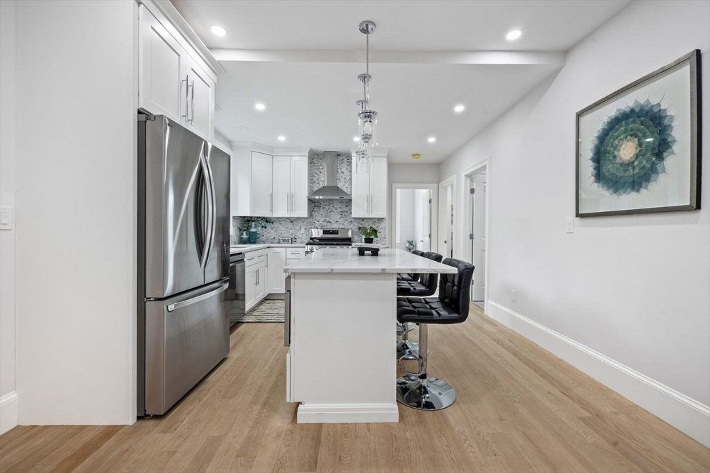 31 Rodman Street, Unit 2 Boston, MA 02130 - Photo 5 of 40 a kitchen with kitchen island a refrigerator a stove a wooden floor and a dining table
