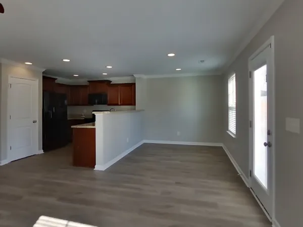 a view of a big room with wooden floor a kitchen and windows