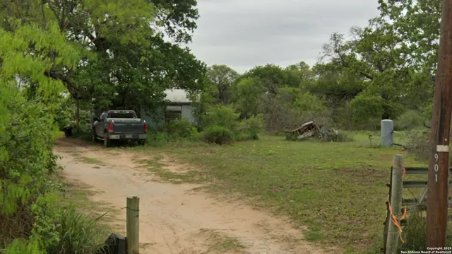 a car parked in front of a yard with trees