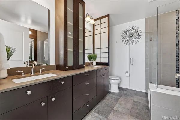 a bathroom with a double vanity sink toilet mirror and windows