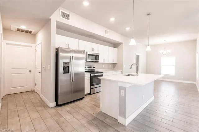 a kitchen with stainless steel appliances a sink a stove a refrigerator and island with wooden floor