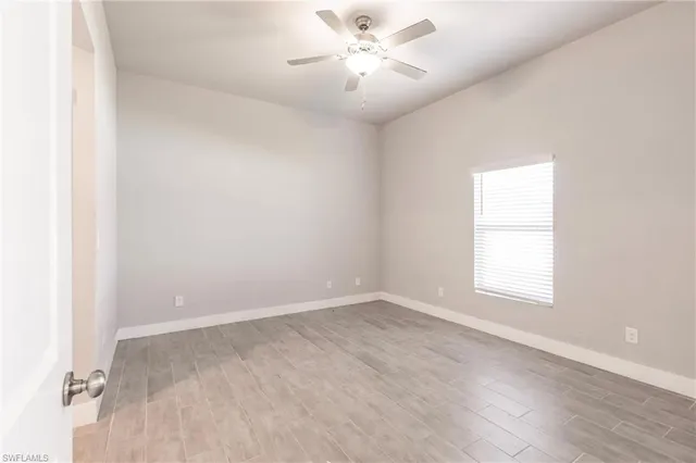 an empty room with a window and a fan