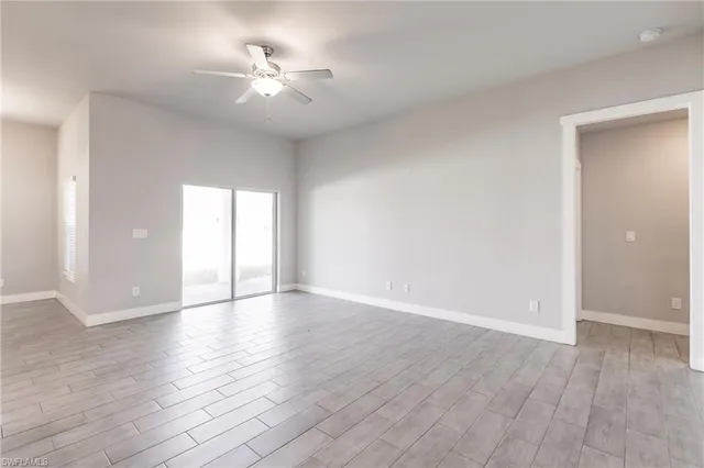 a view of an empty room with a window and wooden floor
