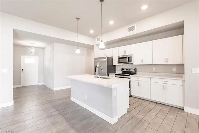 a kitchen with stainless steel appliances granite countertop a stove top oven a sink a refrigerator and white cabinets