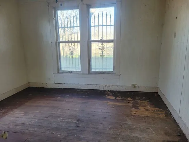 an empty room with wooden floor and window