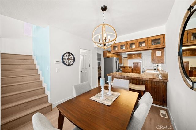 a dining room with wooden floor a chandelier a wooden table and chairs