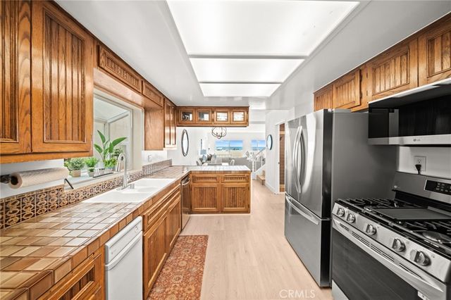 a kitchen with granite countertop stainless steel appliances a refrigerator stove top oven and sink