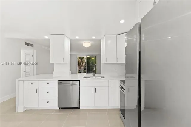 a large kitchen with stainless steel appliances a lot of white cabinets