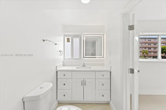 a bathroom with a granite countertop toilet a sink and a mirror