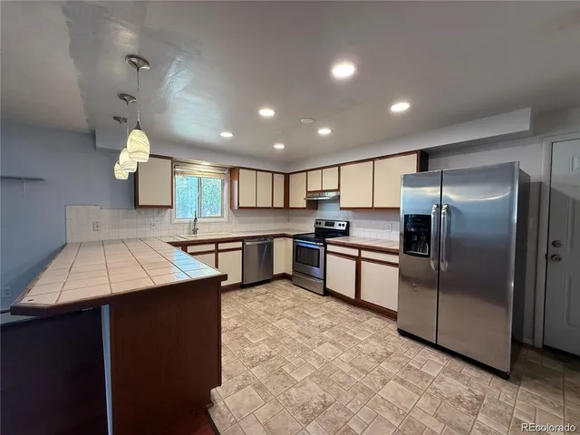 a kitchen with kitchen island a counter top space cabinets stainless steel appliances and a counter top