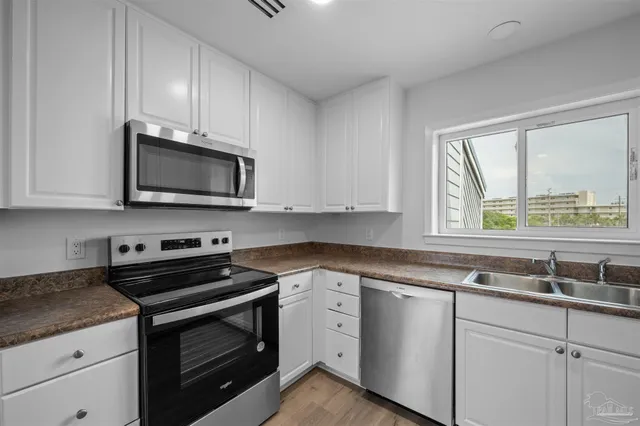 a kitchen with stainless steel appliances granite countertop white cabinets and a stove top oven