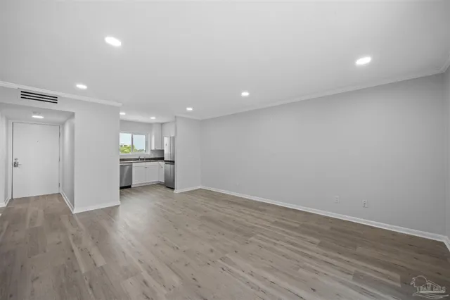 a view of an empty room with wooden floor and window