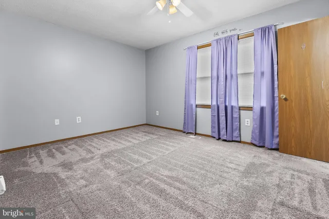 an empty room with closet area and chandelier fan