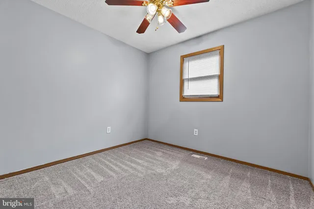an empty room with a window and a ceiling fan