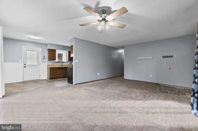 a view of a livingroom with a ceiling fan a flat screen tv and kitchen appliances
