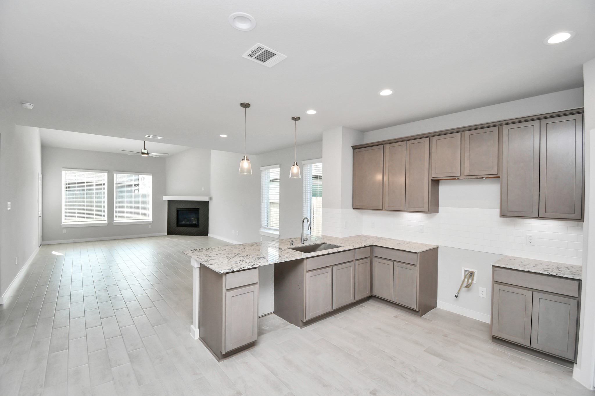 14606 Surfbird Lane Houston, TX 77049 - Photo 11 of 45 This kitchen is truly a chef's dream! This haven Boasts high ceilings, recessed & pendant lighting, stained wood cabinets, granite countertops, stainless steel appliances, a modern tile backsplash. All of this overlooks your expansive family room, creating a perfect space for culinary delights and family gatherings.