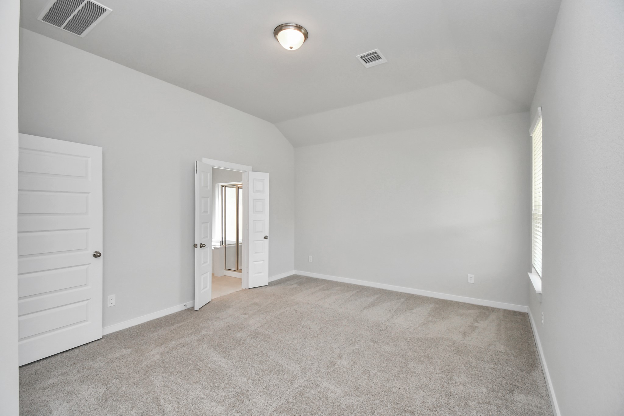 14606 Surfbird Lane Houston, TX 77049 - Photo 22 of 45 Escape and relax in the exquisite primary suite, a haven to unwind after a long day. The spacious room, boasts plush carpeting, soothing paint tones, high ceilings, and expansive windows adorned with privacy blinds.