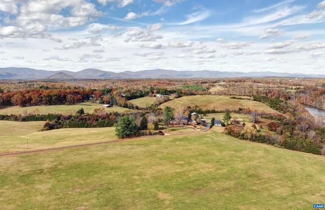 a view of house that has a small yard and large trees with wooden fence