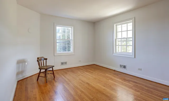 a view of an empty room with window and wooden floor