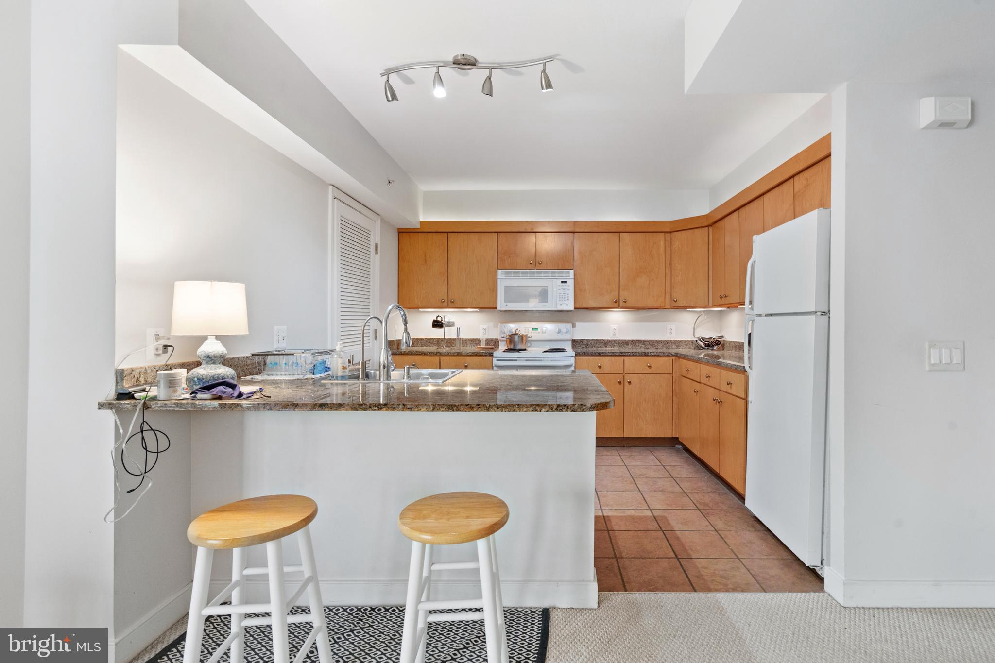 616 E Street Northwest, Unit 304 Washington, DC 20004 - Photo 17 of 53 a kitchen with stainless steel appliances granite countertop a sink a stove a refrigerator cabinets and chairs