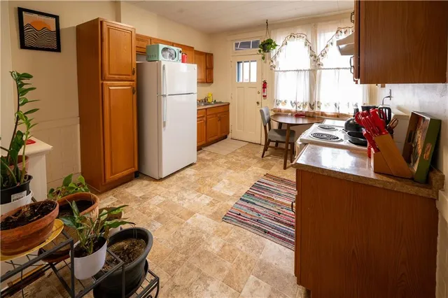 a kitchen with a refrigerator a stove a sink dishwasher and a dining table with wooden floor