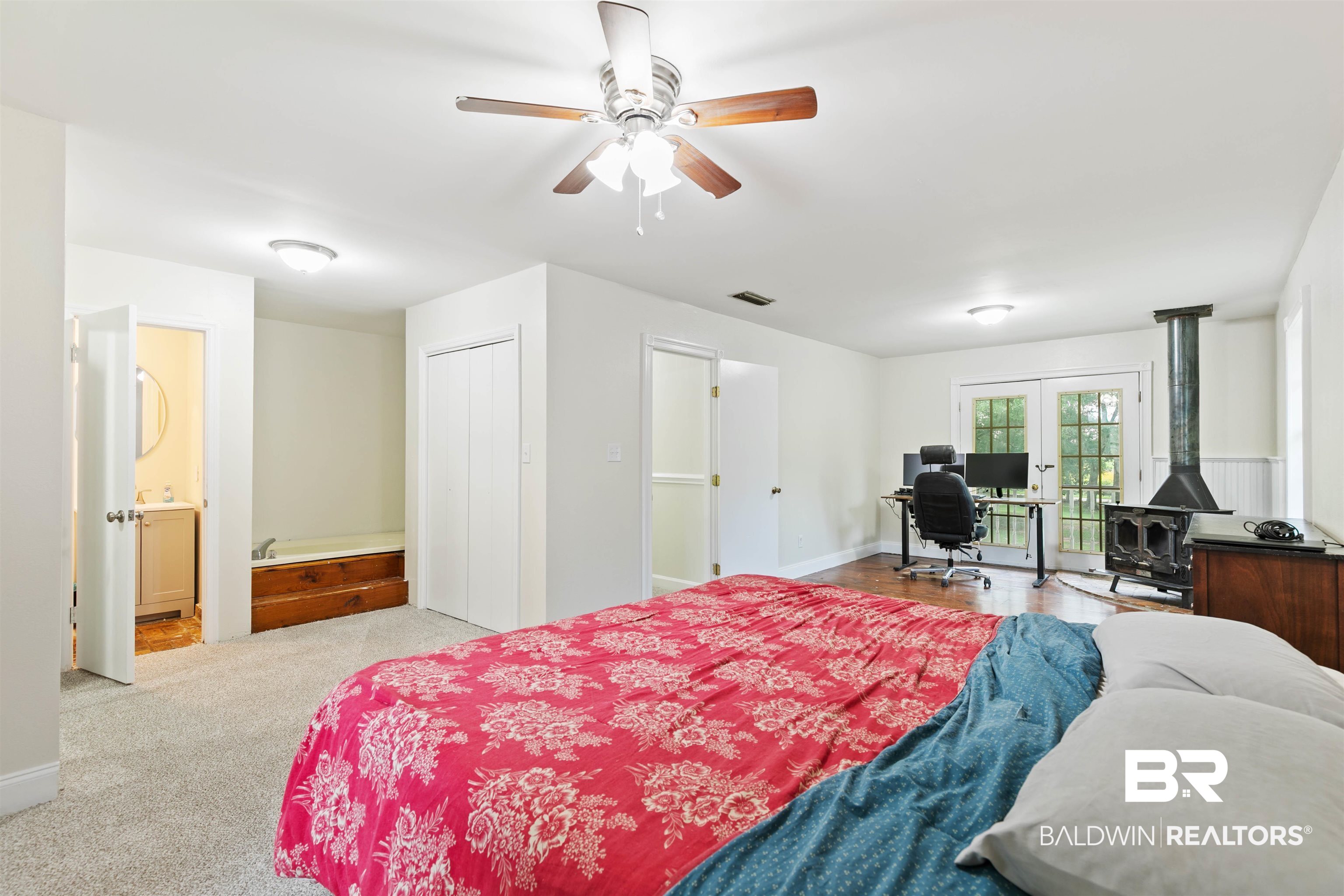 10420 Johnson Road South Mobile, AL 36695 - Photo 42 of 75 Spacious room featuring carpeting, wood-finish flooring, a ceiling fan, and a built-in wood-burning stove with a chimney