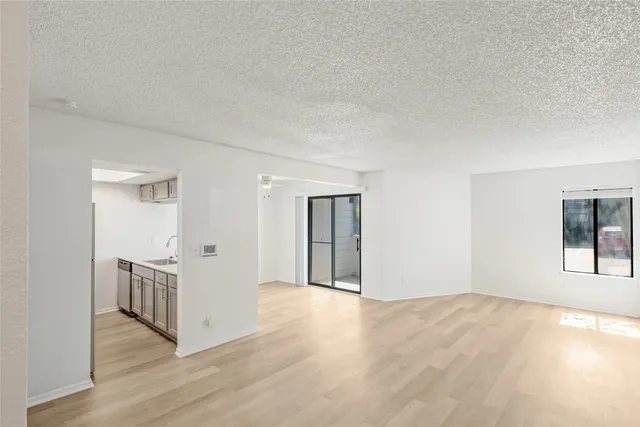 a view of an empty room with wooden floor and windows