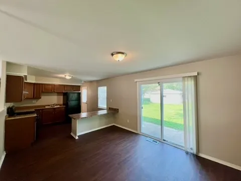 a living room with stainless steel appliances granite countertop furniture and a wooden floor