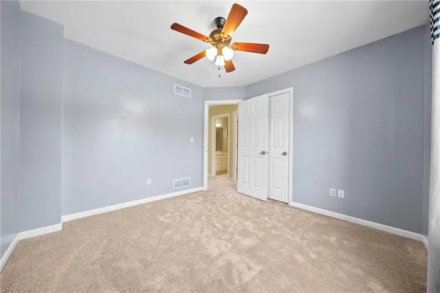 an empty room with closet and a ceiling fan