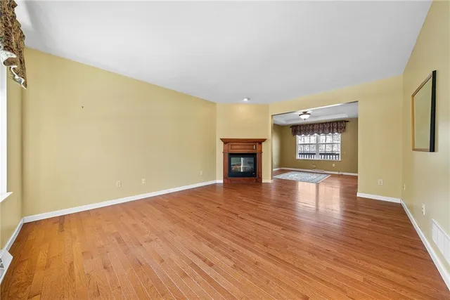 an empty room with wooden floor fire place and a window