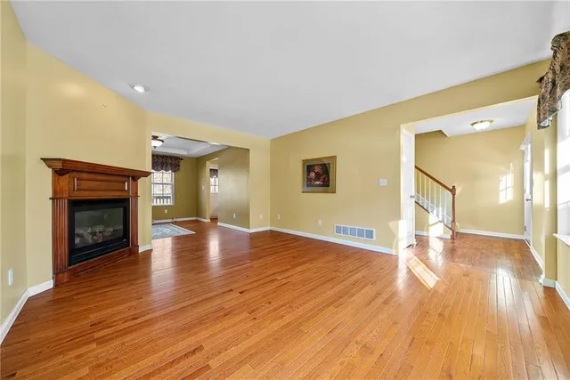a view of empty room with wooden floor and fireplace