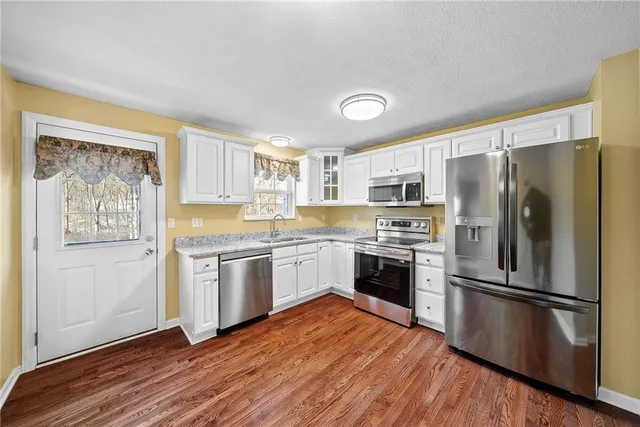 a kitchen with granite countertop stainless steel appliances a sink and a refrigerator