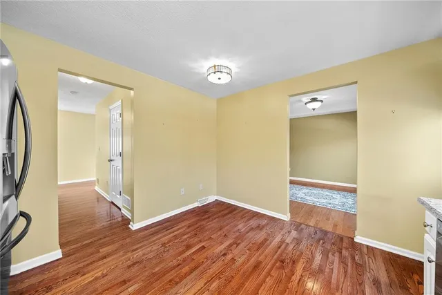 a view of an empty room with wooden floor and a bathroom