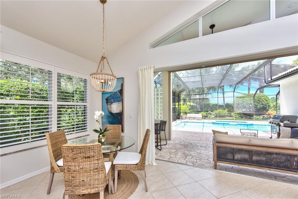 1705 Marsh Run Naples, FL 34109 - Photo 6 of 40 a dining room with wooden floor a chandelier a glass table and chairs