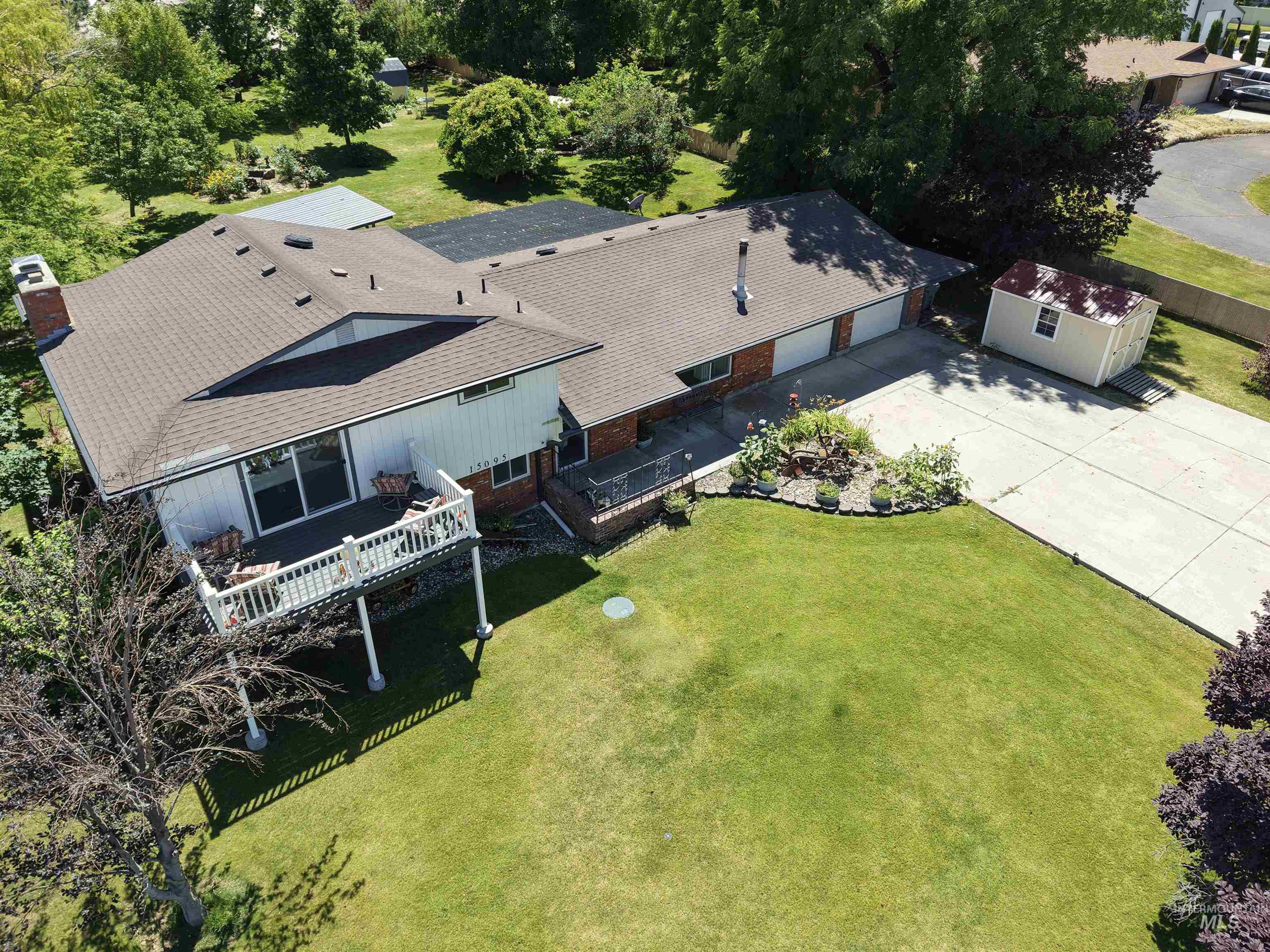 15095 David Street Caldwell, ID 83607 - Photo 34 of 39 Expansive rear yard featuring a raised deck with white railing, a manicured lawn, and mature trees