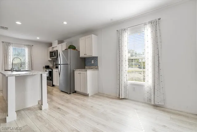 a view of a kitchen with refrigerator and wooden floor