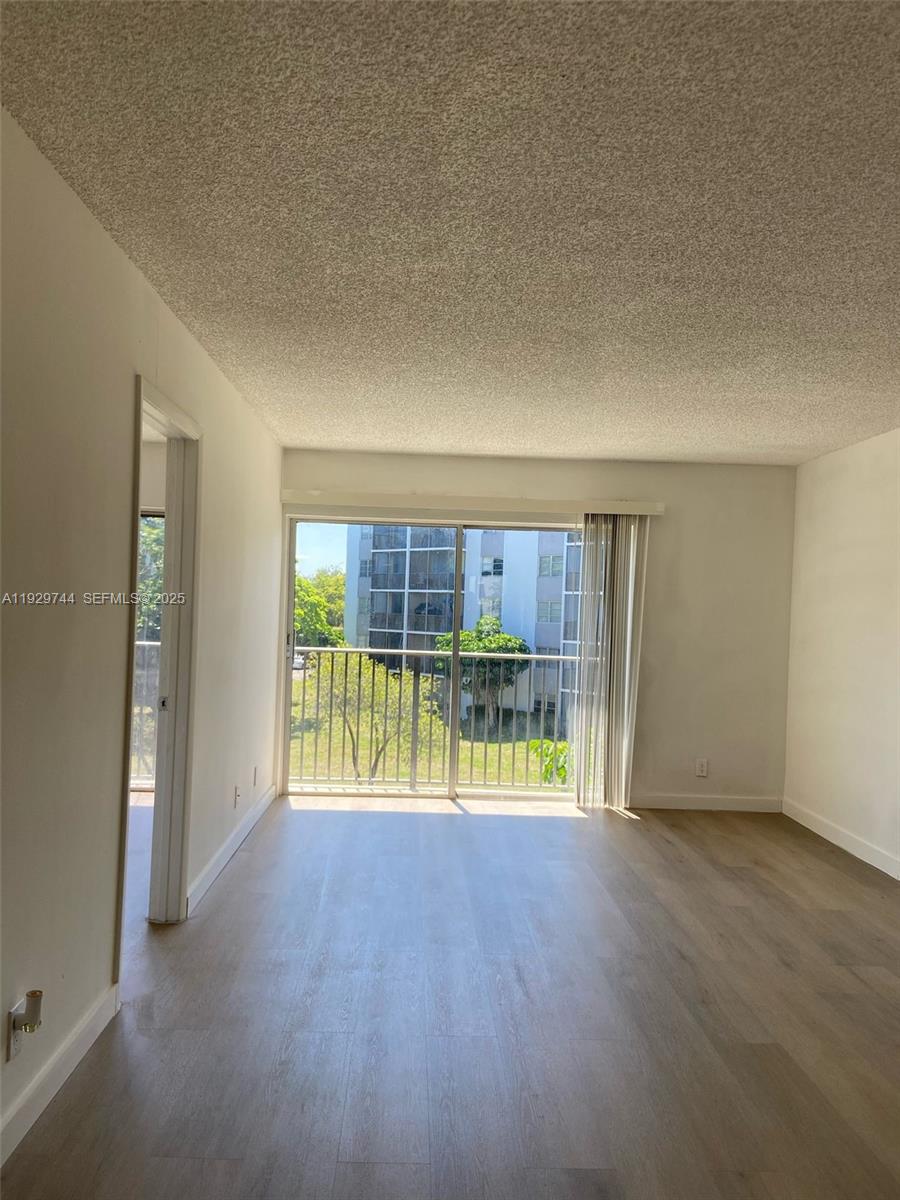 an empty room with floor to ceiling window and wooden floor