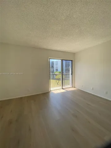 an empty room with wooden floor and fan