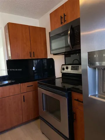 a kitchen with stainless steel appliances granite countertop a stove microwave and sink