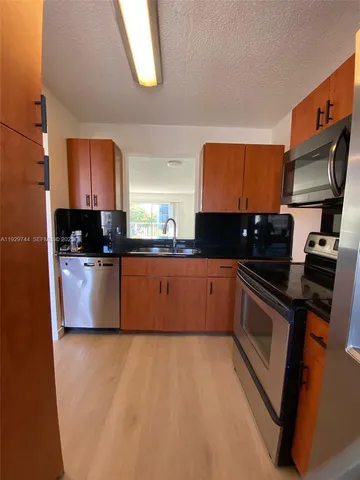 a kitchen with stainless steel appliances granite countertop a stove a sink and a microwave